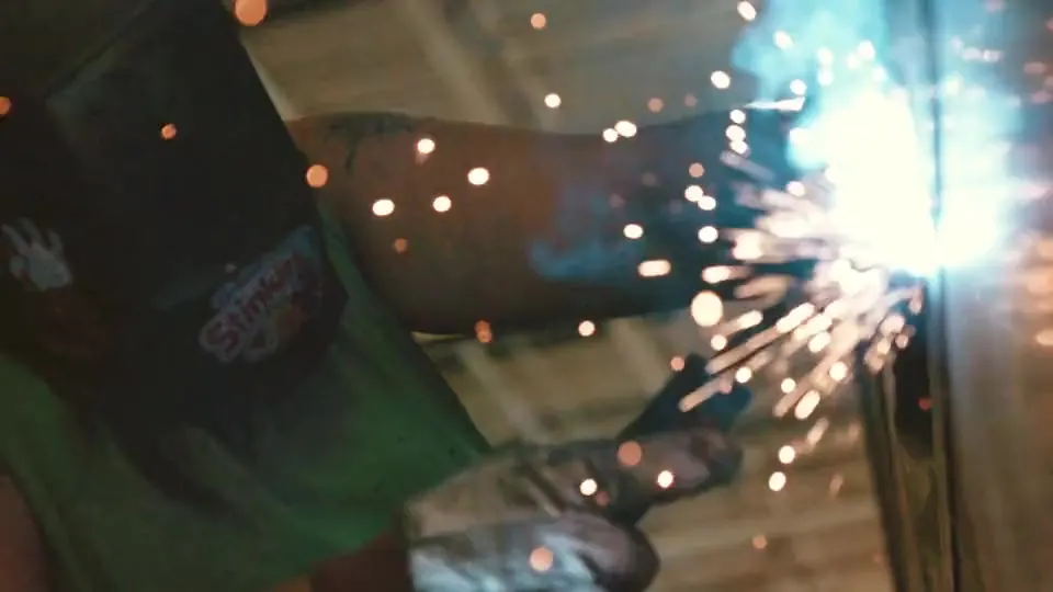 Welder at work, sparks against dark steel